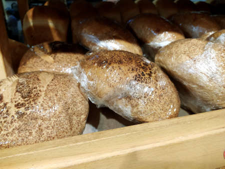 Freshly baked bread wrapped in plastic wrap lies on a store shelf.の写真素材