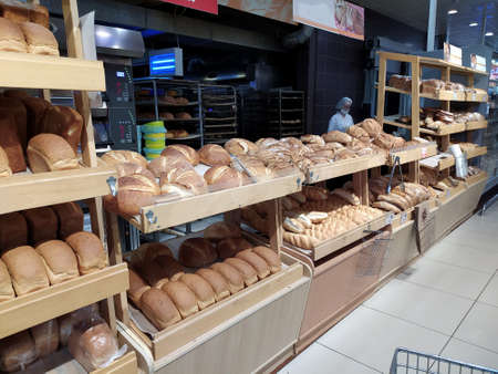 Freshly baked loaves of bread lie on a tray in a bakery, in the background there is a hot oven.のeditorial素材