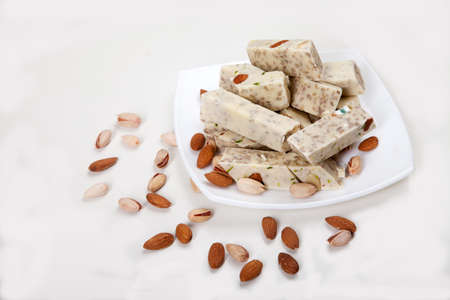 Halva made from sunflower seeds, almonds and pistachios lies on a plate on a white background. Copy spaes.の写真素材