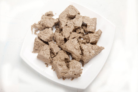 Large pieces of halva lie on a porcelain plate on a white background.の写真素材