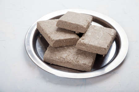 Halva from sunflower seeds in briquettes in a metal plate stands on a white background.の写真素材