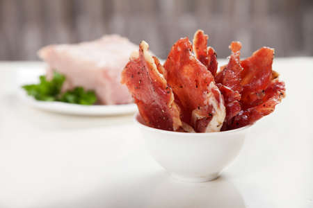 Jerky in a cup and raw meat with herbs on a white plate.の写真素材