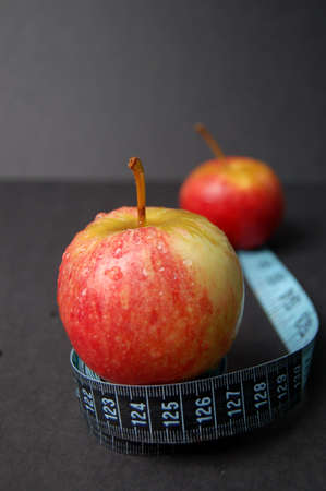 This is an image of a two apples and a measuring tape. The distance between the two apples represents progress in dieting.の写真素材