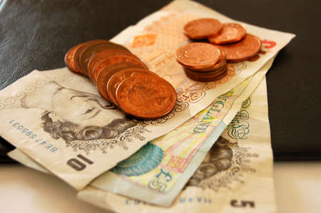 This is an image of some pound notes and coins, on top of a portfolio.