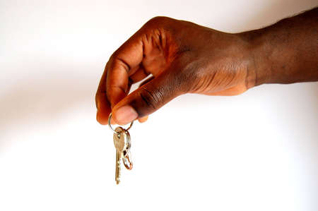 This is an image of a hand offering a key. This can be used to represent real-estate,  relocation etc..の写真素材