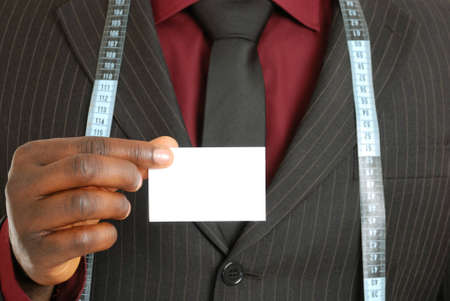 This is an image of a business man wearing a measuring tape and holding a business card.の写真素材
