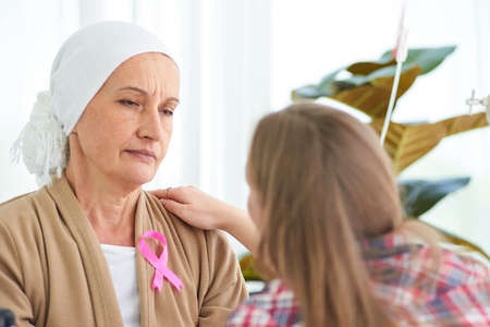 White caucasian female hairless and eyebrowless feel bad are praying and waiting for chemotherapy  in hospital room, breast cancer awareness month concept.の写真素材