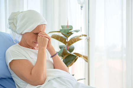 White caucasian female hairless and eyebrowless feel bad are praying and waiting for chemotherapy  in hospital room, breast cancer awareness month concept.の写真素材