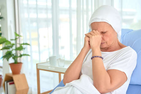 White caucasian female hairless and eyebrowless feel bad are praying and waiting for chemotherapy  in hospital room, breast cancer awareness month concept.の写真素材