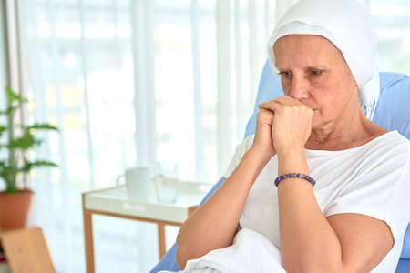 White caucasian female hairless and eyebrowless feel bad are praying and waiting for chemotherapy  in hospital room, breast cancer awareness month concept.の写真素材
