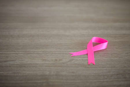 Pink silk ribbon on wooden desk, Breast cancer awareness mont concept for background.の写真素材