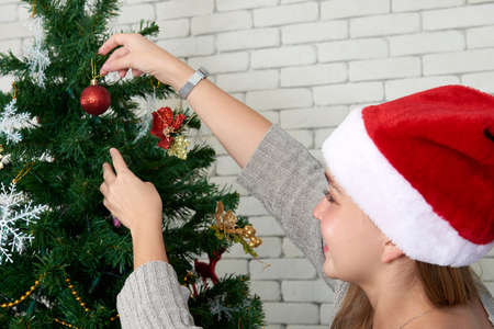 Young white caucasian female wearing sata claus hat with smile decorate christmas / pine tree indoor for Merry christmas and Happy new year holidaysの写真素材