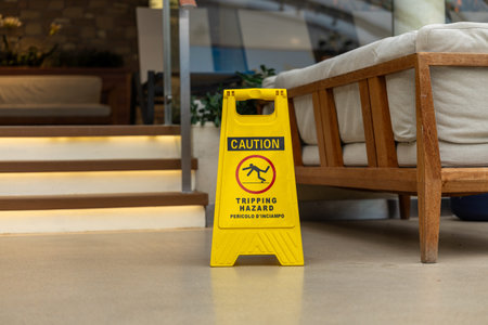 Yellow caution tripping hazard sign near staircase indoor safety prevention concept.の写真素材