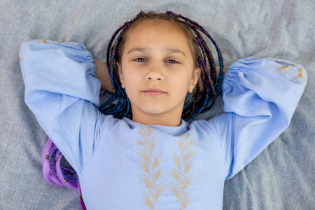 Close-up portrait of a young girl resting on a picnic blanket outdoors.