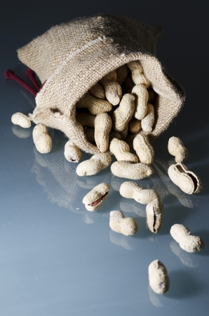 Peanuts in shell in organic bag, on glass tableの写真素材