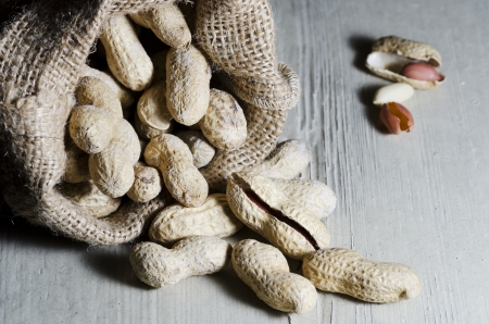 Peanuts in shell in organic bag, on white wooden table