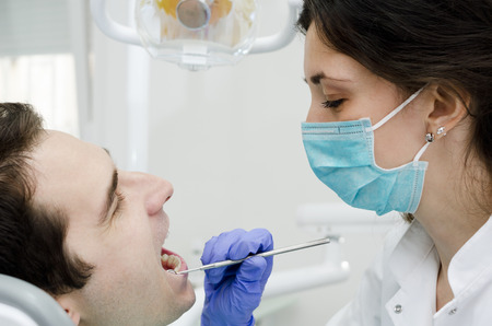 Young male with open mouth during oral checkup at the dentistの写真素材