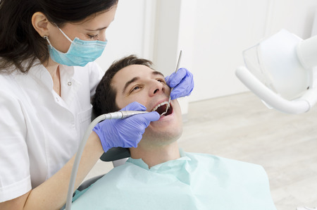 Young male with open mouth during oral checkup at the dentistの写真素材