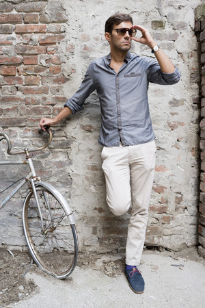 Casual young man stands with his back against a brick wallの写真素材