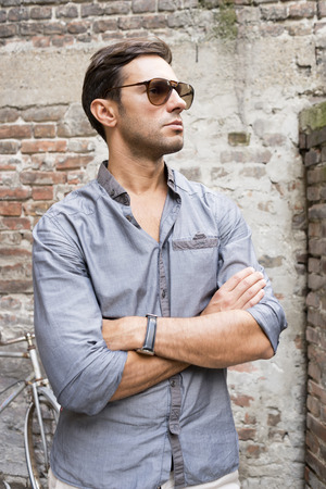 Casual young man stands with his back against a brick wallの写真素材