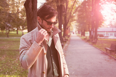 Handsome man wearing trench coat in parkの写真素材