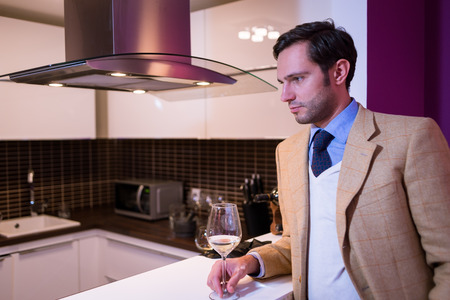 Handsome man, drinking white wine at homeの写真素材