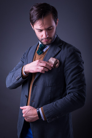 Handsome man in suit with tie and pocket square, fixing his pocket squareの写真素材