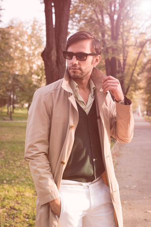 Handsome man wearing trench coat in parkの写真素材