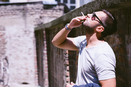 Casual young man outdoors,l with a cigaretteの写真素材