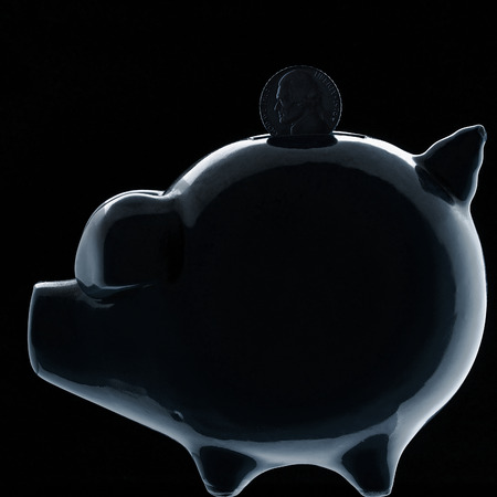 piggy bank silhouette on black with dime stuck inの写真素材