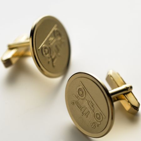 a pair of golden cuff links on white