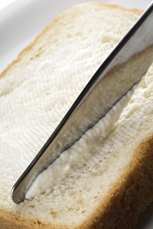 a butter knife spreading a cream cheese over the bread