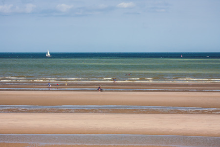 Beach with people, sea, sand, sky and boatの写真素材