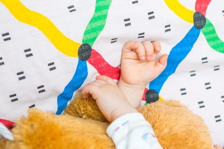 close up of toddler hands sleeping in teddy bear in bed
