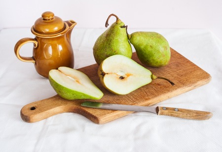 green pears, wooden cutting board and knife on table with tableclothの写真素材
