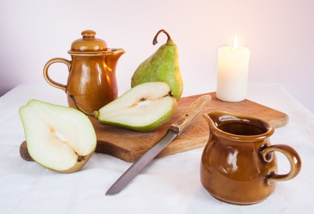 green pears, wooden cutting board and knife on table with tableclothの写真素材
