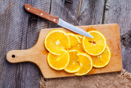 Orange slices and cutting board on old wooden tableの写真素材