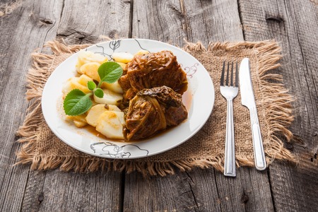 Tasty stuffed cabbage dish in white plate on old wooden table. Polish traditional food
