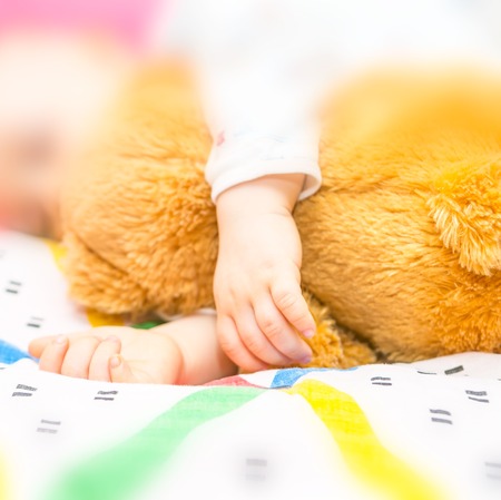 close up of toddler hands sleeping with teddy bear in bedの写真素材