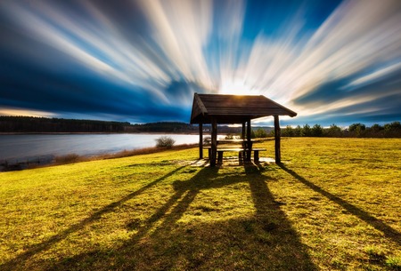 Beautiful landscape of wooden hut under dramatic sky photographed on long exposure. Landscape with bad weather and vibrant colors.の写真素材