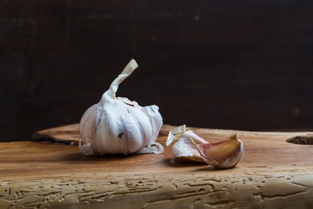 garlic bulbs on rustic wooden cutting board and wooden table. mystic light studio shotの写真素材