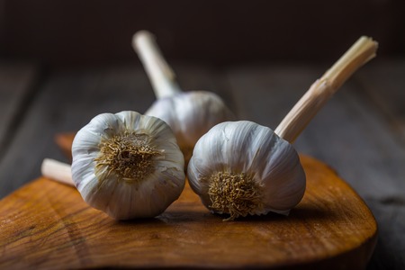 garlic bulbs on rustic wooden cutting board and wooden table. mystic light studio shotの写真素材