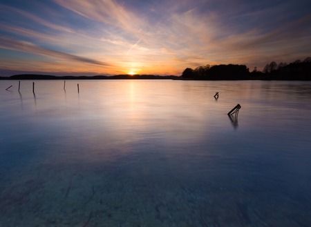 Beautiful sunset over calm lake in Mazury lake district. After sunset sky reflecting in water, calm vibrant landscape. Krzywe lake near Olsztyn, Poland.の写真素材
