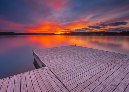 Beautiful lake landscape with vibrant sunset and pier. Long exposure landscape.の写真素材