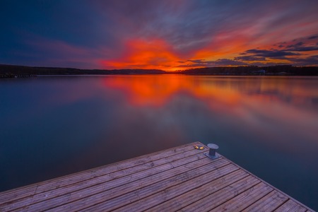 Beautiful lake landscape with vibrant sunset and pier. Long exposure landscape.の写真素材