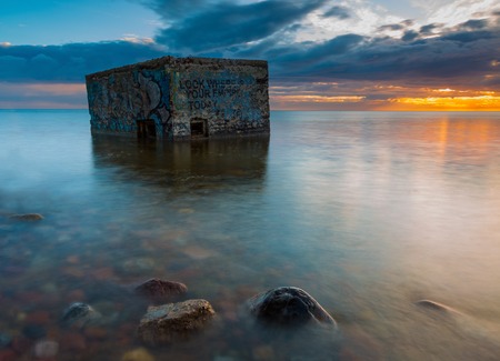 Rocky sea shore with world war II military bunker. Long exposure photo. Baltic sea shore.の写真素材