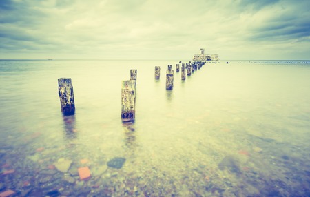 Vintage photo of beautiful view on Baltic sandy coast with old military buildings from world war II and wooden breakwaters. Long exposure photoの写真素材
