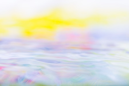 Moving water abstraction. Close up of water surface with colorful reflections