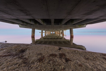 Landscape of Gdanska bay with pier in Jastarnia photographed before sunrise.Landscape with pastel colors of sunrise. Moon setting over sea.の写真素材
