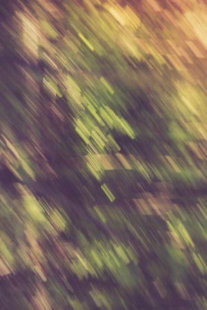 Vintage photo of blurry abstract background of green summer forest photographed on long exposure with motion effect.の写真素材